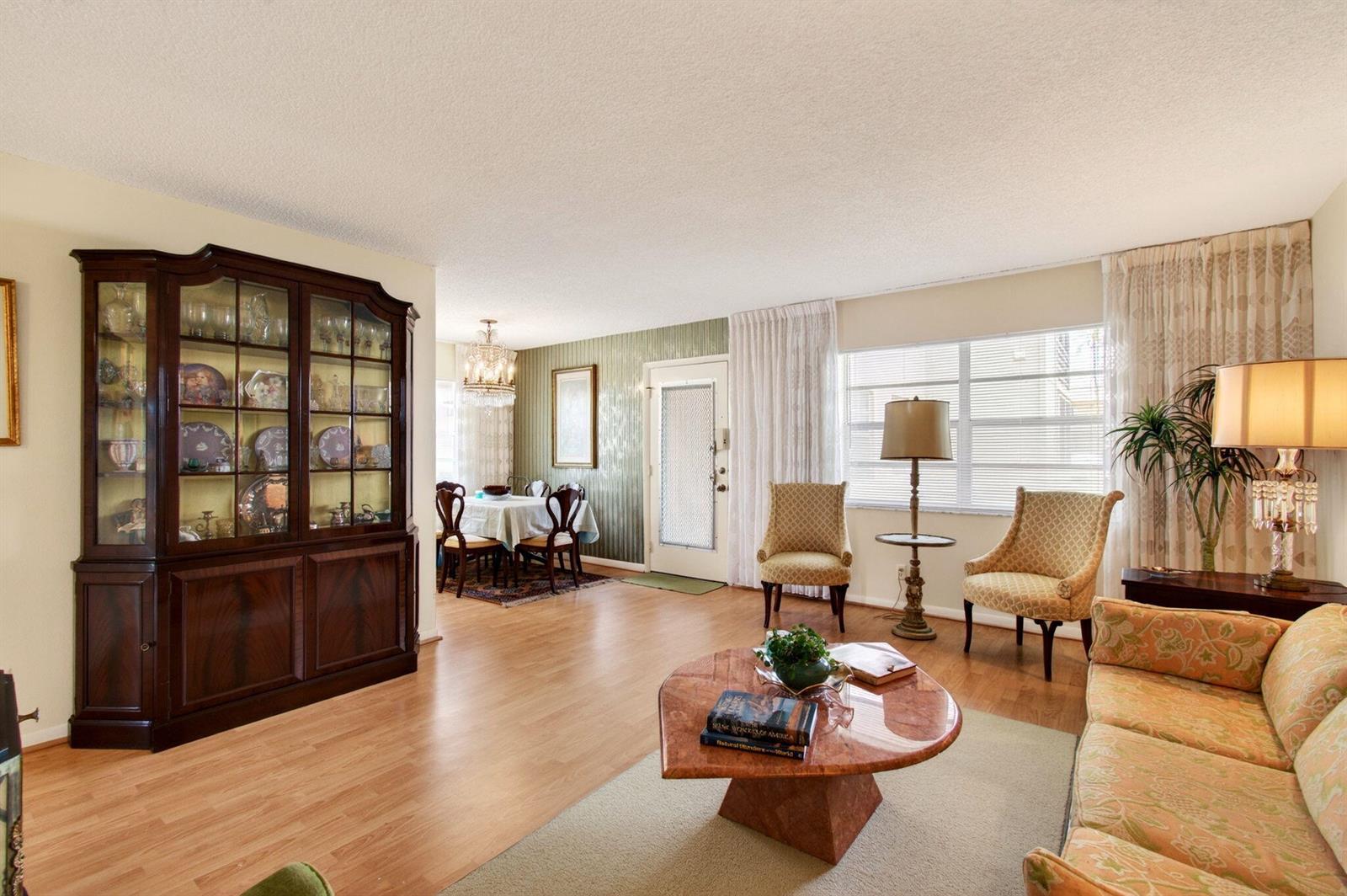 A living room with wood floors, a large china cabinet, and a dining area beyond — 349 Capri # H, Delray Beach FL 33484, DELRAY BEACH, FL