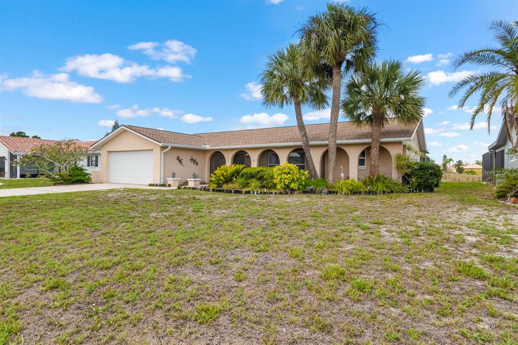 A single-story house with a tan exterior, arched entryway, and palm trees in the front yard — 736 FLAMINGO DRIVE, APOLLO BEACH, FL