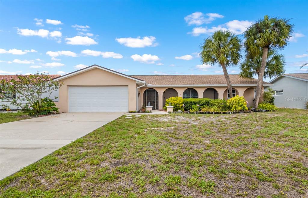 A single-story house with a beige exterior, a two-car garage, and arched porch entryways — 736 FLAMINGO DRIVE, APOLLO BEACH, FL