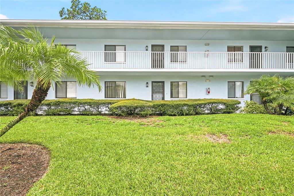 A two-story apartment building with a white balcony and green landscaping in front — 205 MARTHA LANE UNIT 205, OLDSMAR, FL