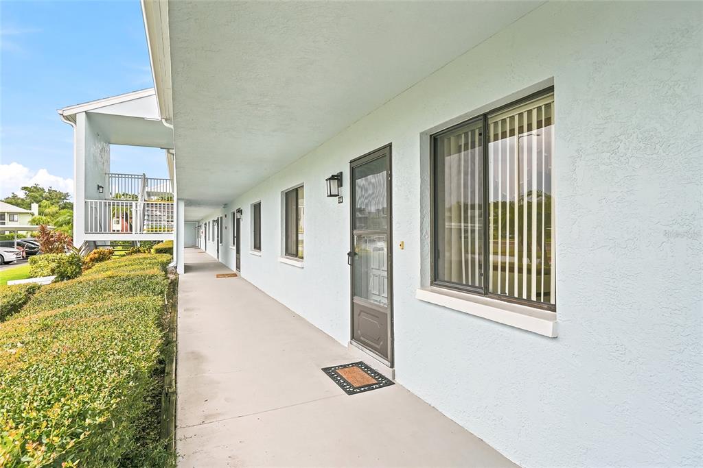 An exterior walkway leads past several apartment doors and windows along a light-colored building — 205 MARTHA LANE UNIT 205, OLDSMAR, FL