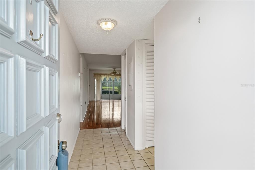 An entryway with tile flooring leads to a living area with wood floors and sliding doors — 205 MARTHA LANE UNIT 205, OLDSMAR, FL