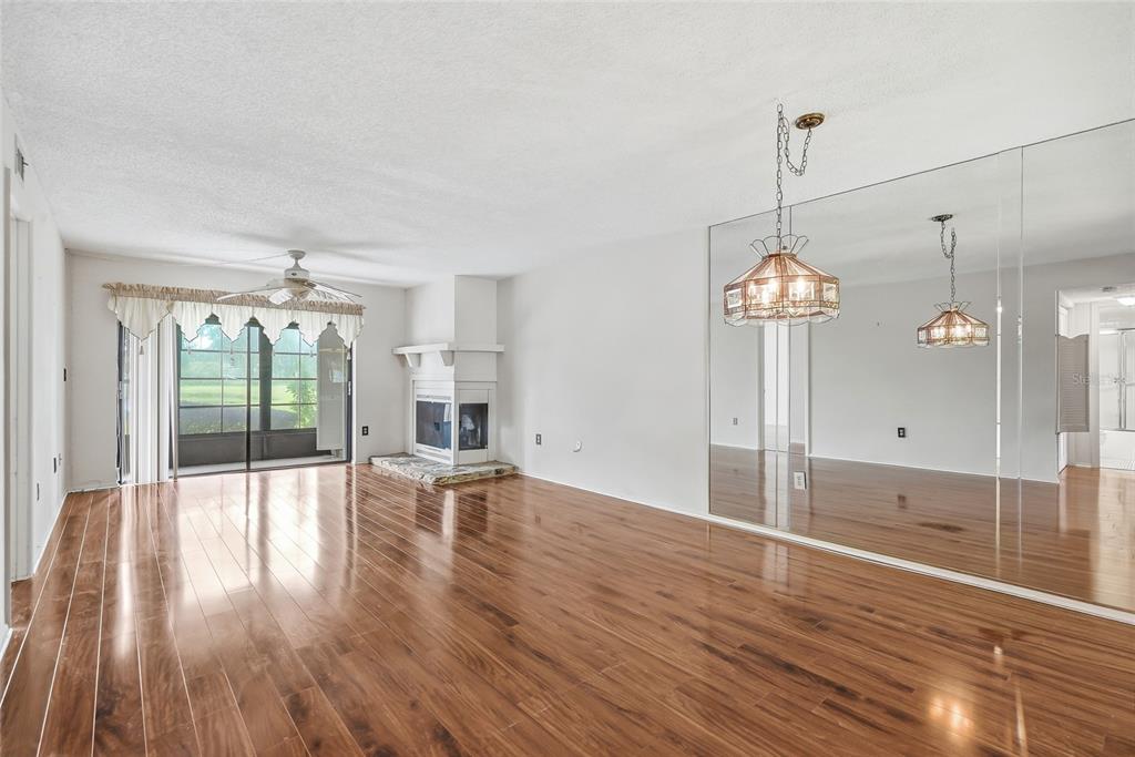 A living room with wood-look flooring, a fireplace, a mirrored wall, and sliding glass doors — 205 MARTHA LANE UNIT 205, OLDSMAR, FL