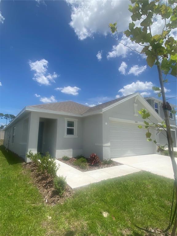 A single-story house with a gray stucco exterior, a two-car garage, and a front walkway — 11519 MEMORIAL DRIVE, BROOKSVILLE, FL