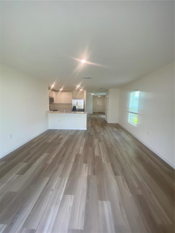An open-concept living area features light wood-look flooring and a kitchen with white cabinetry — 11519 MEMORIAL DRIVE, BROOKSVILLE, FL