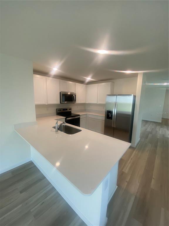 A kitchen features white cabinets, stainless steel appliances, and a quartz countertop island with sink — 11519 MEMORIAL DRIVE, BROOKSVILLE, FL
