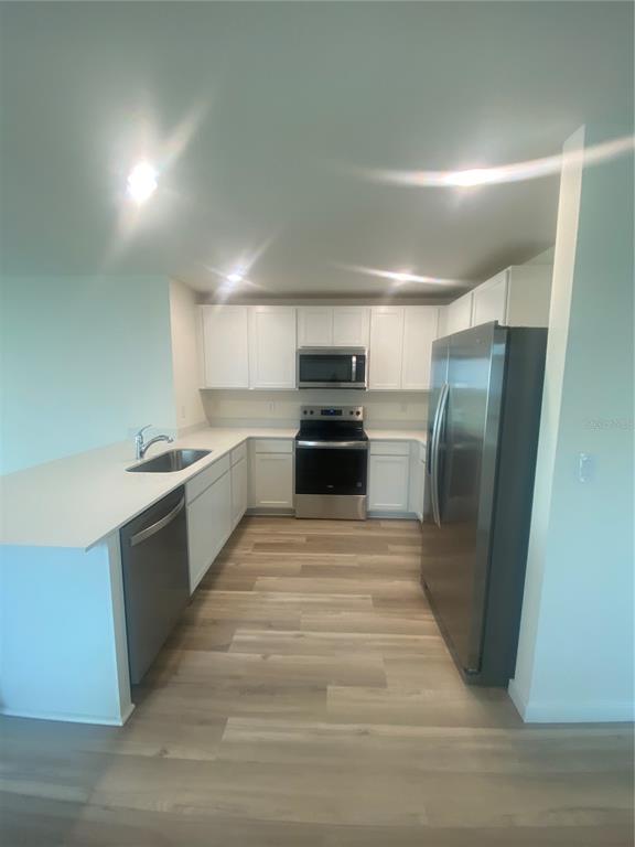 A modern kitchen features white cabinets, stainless steel appliances, and light wood-look flooring — 11519 MEMORIAL DRIVE, BROOKSVILLE, FL
