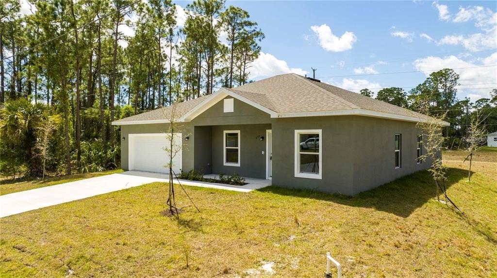 A single-story house with a gray stucco exterior, a white garage door, and a front porch — 971 WELLINGTON STREET SW, PALM BAY, FL