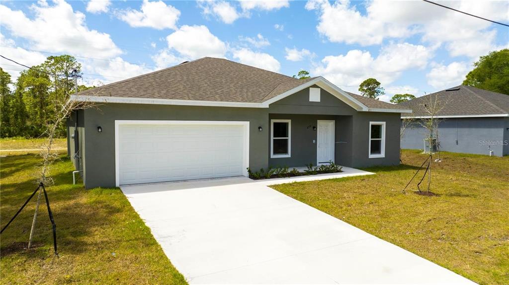 A single-story gray house with a two-car garage sits on a grassy lot — 971 WELLINGTON STREET SW, PALM BAY, FL