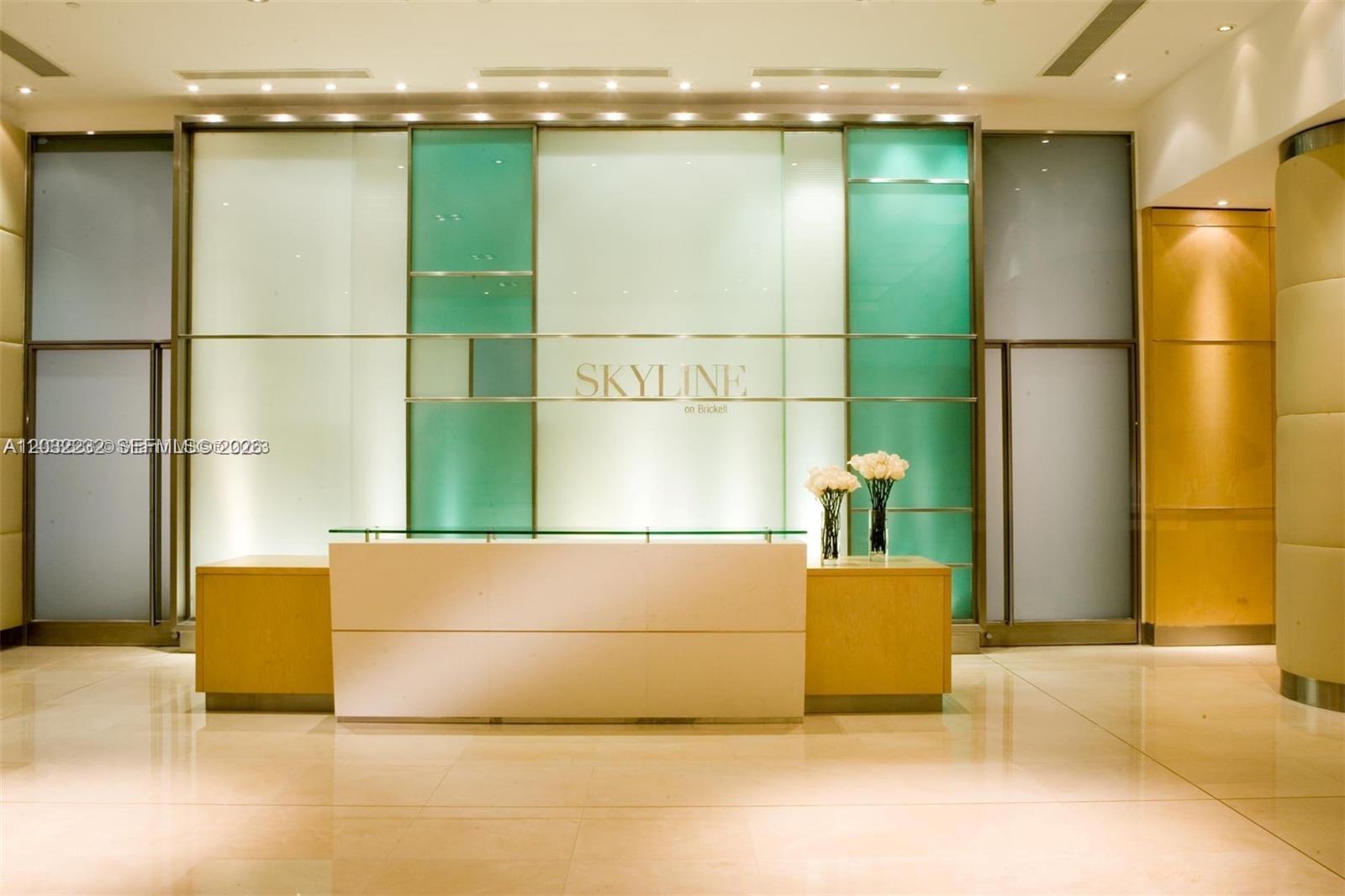 A modern lobby features a reception desk in front of a glass and metal wall — 2101 Brickell Ave # 2402, Miami FL 33129, MIAMI, FL