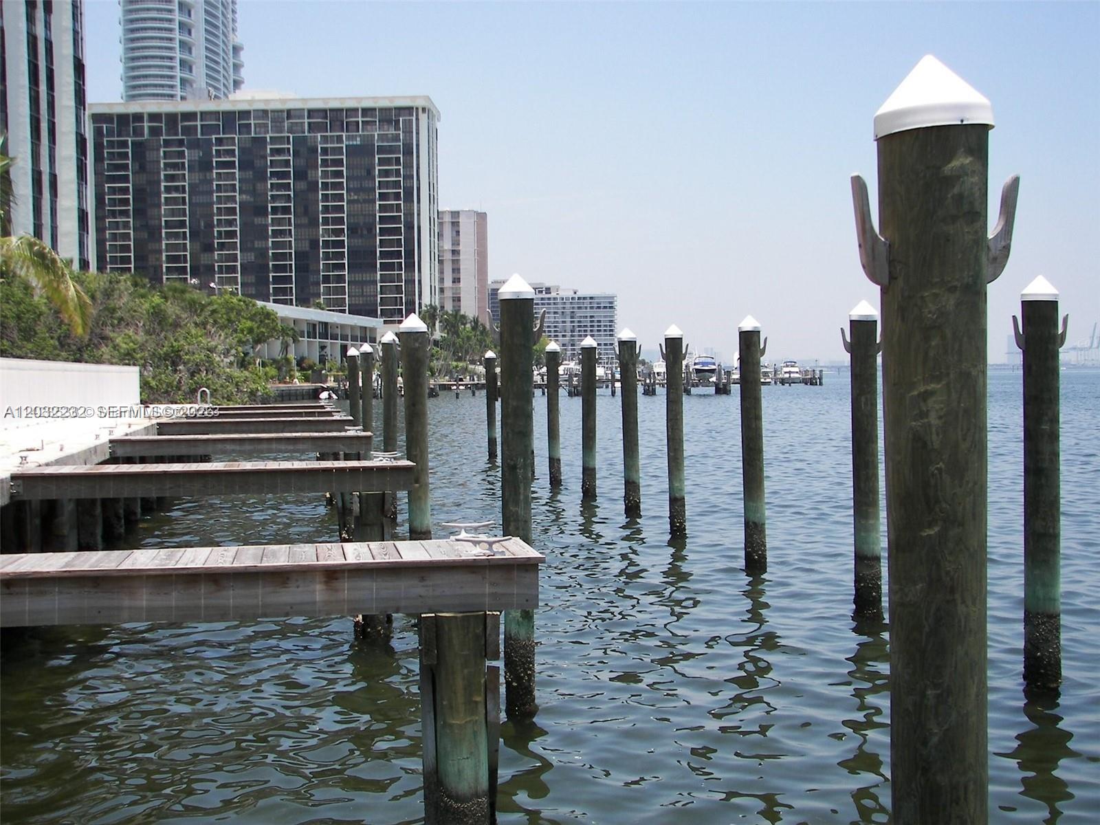A wooden dock extends into the water past several mooring pilings toward distant high-rise buildings — 2101 Brickell Ave # 2402, Miami FL 33129, MIAMI, FL