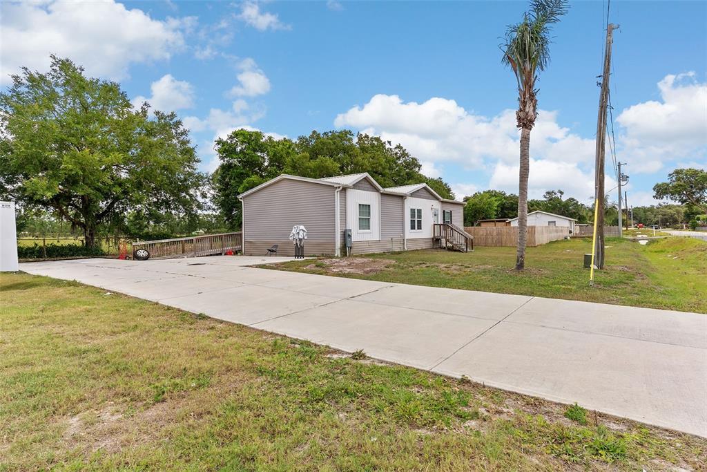 A single-story manufactured home with light siding sits on a large lot with a driveway — 8010 PALMER ROAD, BARTOW, FL