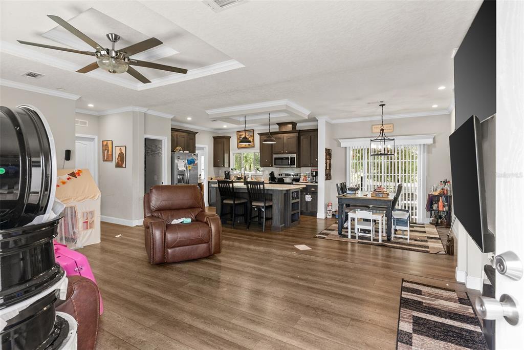 An open-concept living area features wood-look flooring, a kitchen island, and a dining space — 8010 PALMER ROAD, BARTOW, FL