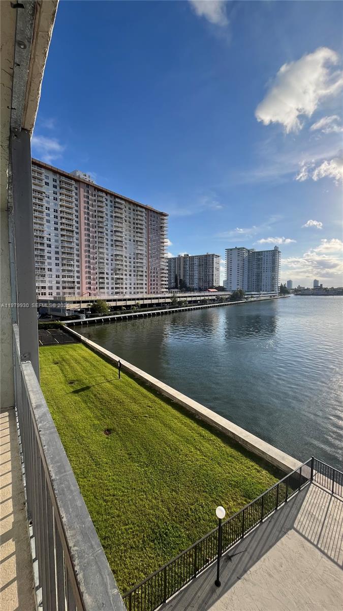 A balcony overlooks a grassy lawn, a canal, and several high-rise apartment buildings — 17500 N Bay Rd # S403, Sunny Isles Beach FL 33160, SUNNY ISLES BEACH, FL