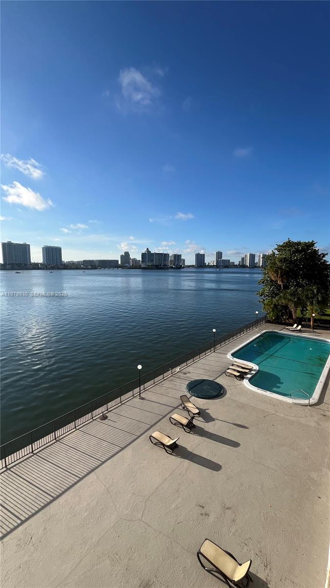 An elevated view of a swimming pool and patio overlooking a large body of water — 17500 N Bay Rd # S403, Sunny Isles Beach FL 33160, SUNNY ISLES BEACH, FL