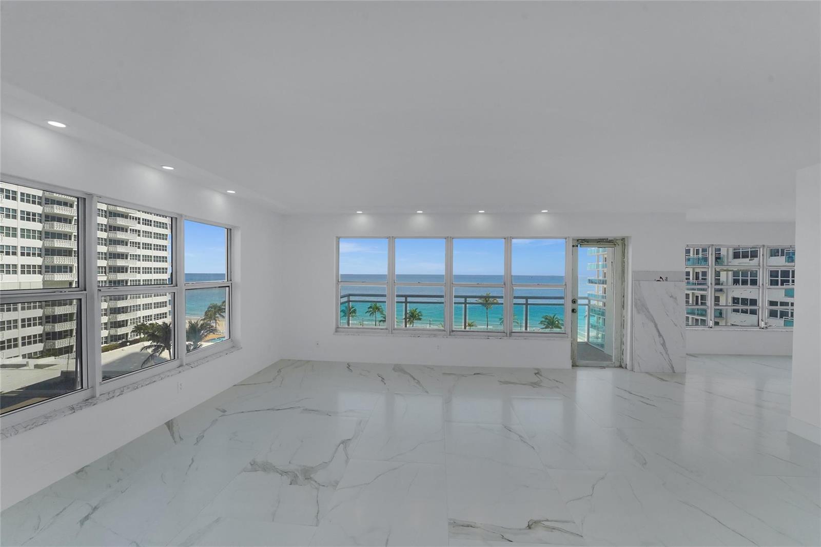 A bright, empty room features white marble flooring, recessed lighting, and large windows overlooking the ocean — 3900 Galt Ocean Drive # 511, Fort Lauderdale FL 33308, FORT LAUDERDALE, FL