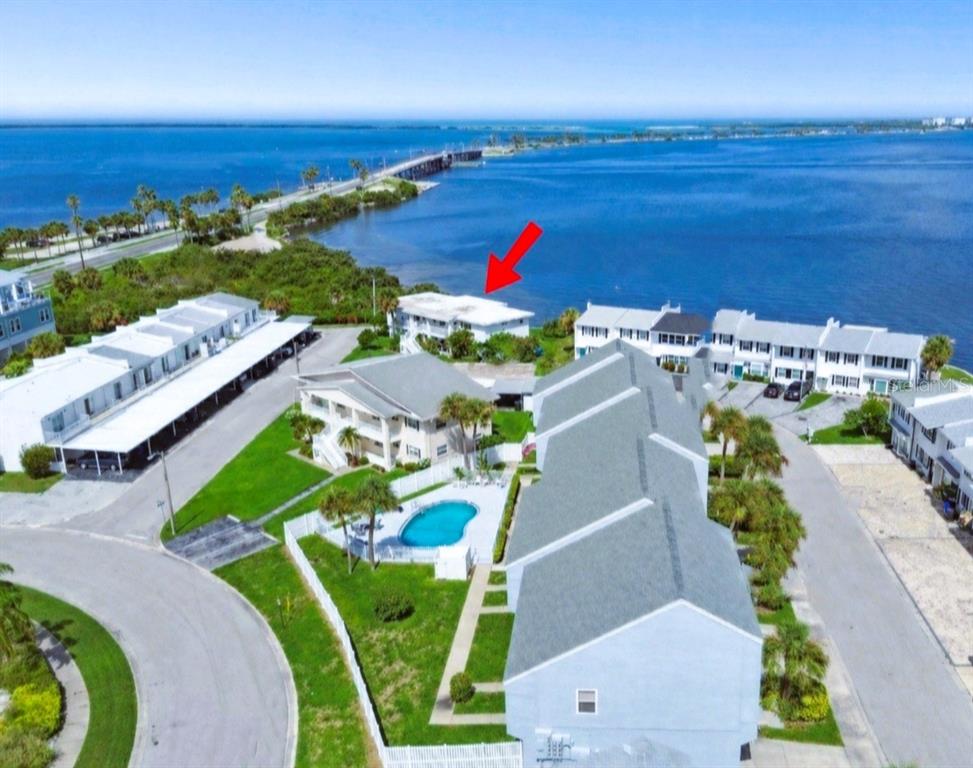 An aerial view shows a waterfront residential complex with a pool and a red arrow — 2616 ST JOSEPHS DRIVE W UNIT 1, DUNEDIN, FL