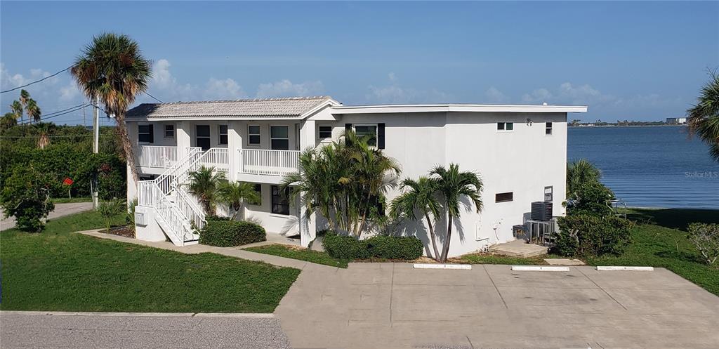 A two-story white apartment building sits near a body of water with a parking lot — 2616 ST JOSEPHS DRIVE W UNIT 1, DUNEDIN, FL