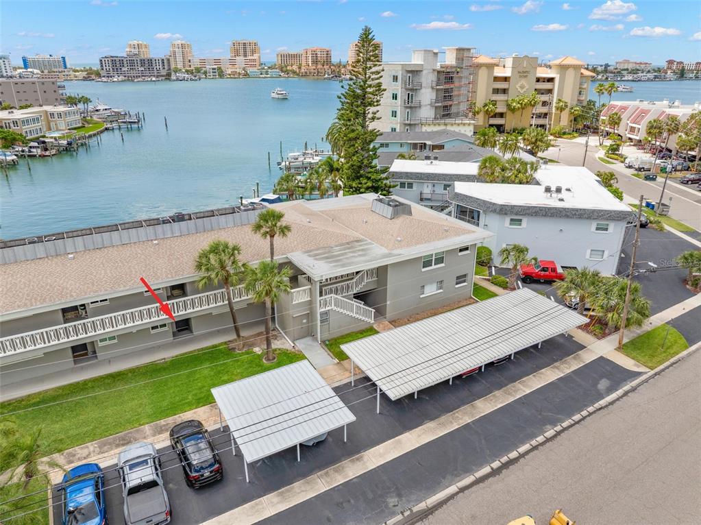 An aerial view shows a multi-story apartment building with a red arrow pointing to a unit — 400 LARBOARD WAY UNIT 106, CLEARWATER BEACH, FL