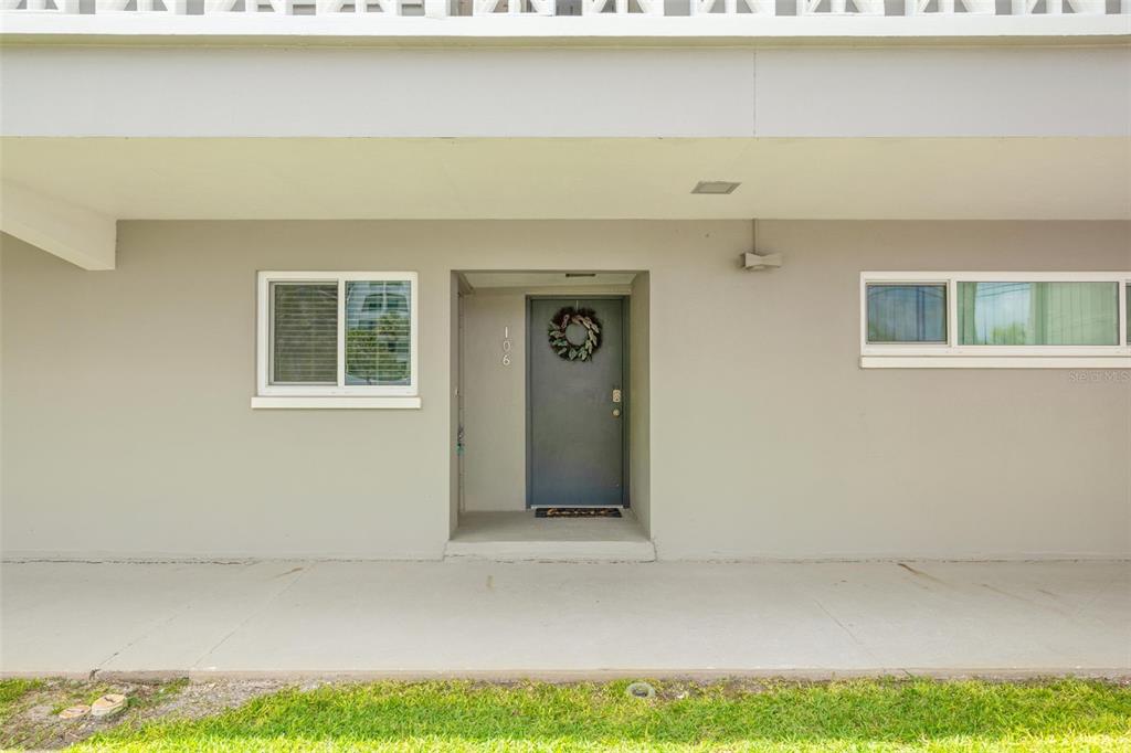 The exterior view shows a ground-level apartment entrance with a gray door and windows — 400 LARBOARD WAY UNIT 106, CLEARWATER BEACH, FL