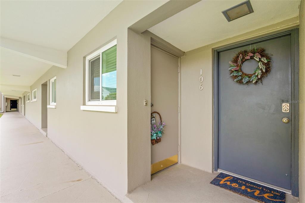An exterior view of a building hallway showing apartment doors and a concrete walkway — 400 LARBOARD WAY UNIT 106, CLEARWATER BEACH, FL