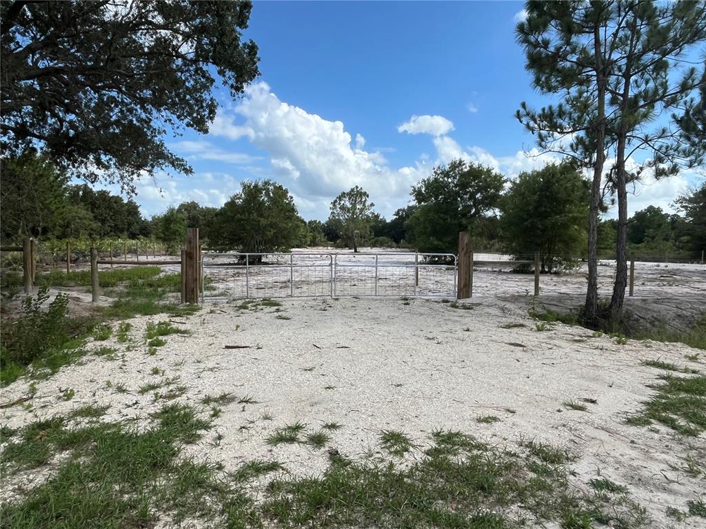 A metal gate stands at the entrance of a sandy, fenced-in plot of land — 16916 NW 262ND STREET, OKEECHOBEE, FL