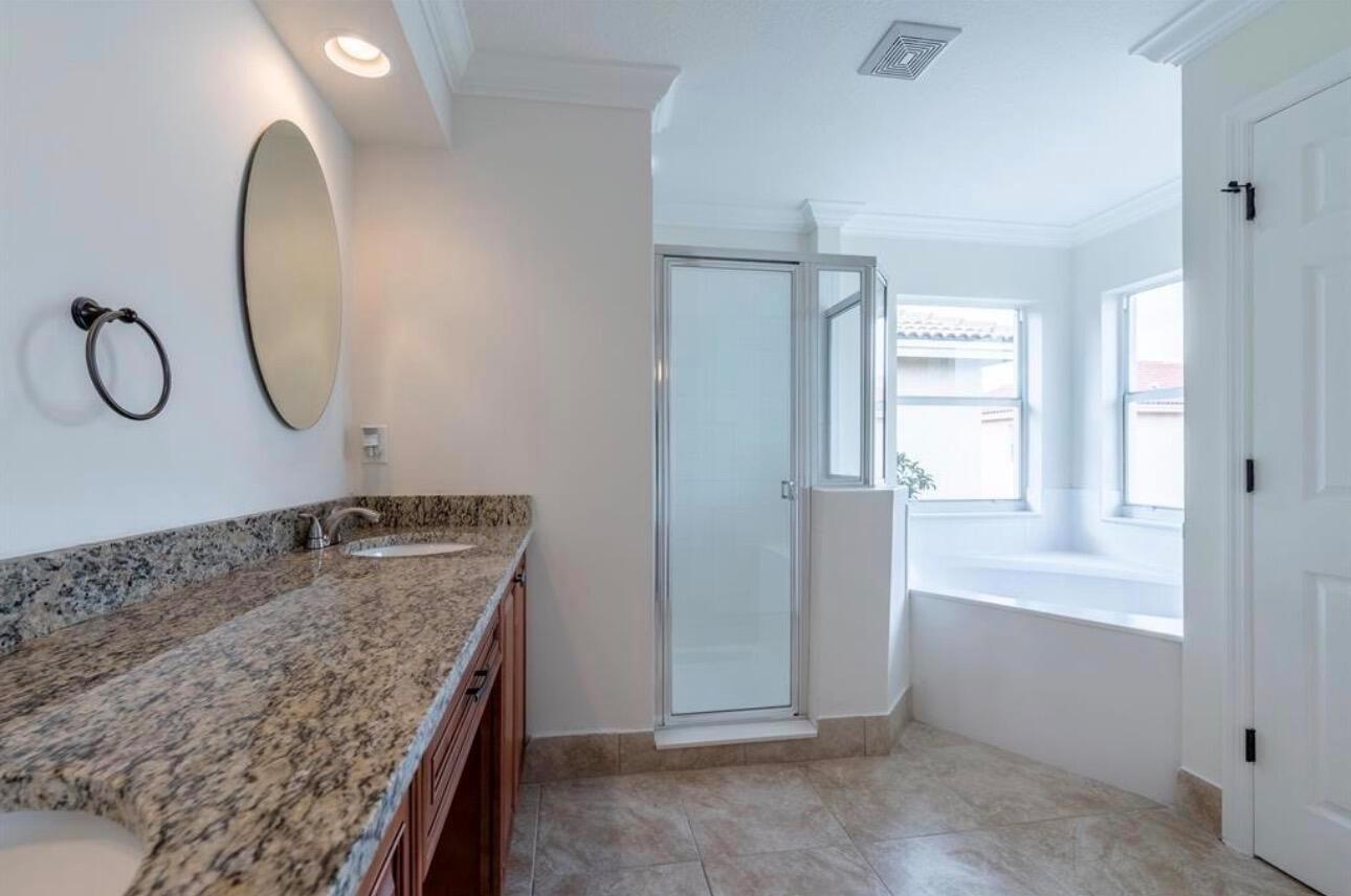 A bathroom features a granite vanity, a glass-enclosed shower, and a soaking tub by windows — 4147 Meade Way, West Palm Beach FL 33409, WEST PALM BEACH, FL