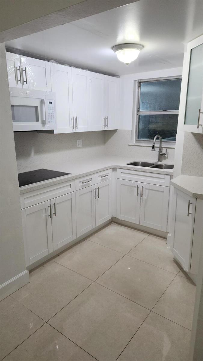 A kitchen with white cabinets, light countertops, stainless steel appliances, and large floor tiles — 210 Fontainebleau Boulevard # 311, Miami FL 33172, MIAMI, FL