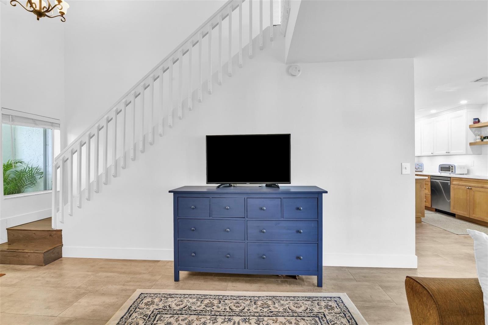 A blue dresser with a television sits in a living area beside a white staircase — 843 NW 98th Avenue, Plantation FL 33324, PLANTATION, FL