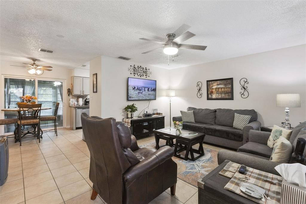A living room features tile flooring, a ceiling fan, a sofa, and a television — 12532 ORANGEWOOD COURT UNIT 0, TAVARES, FL