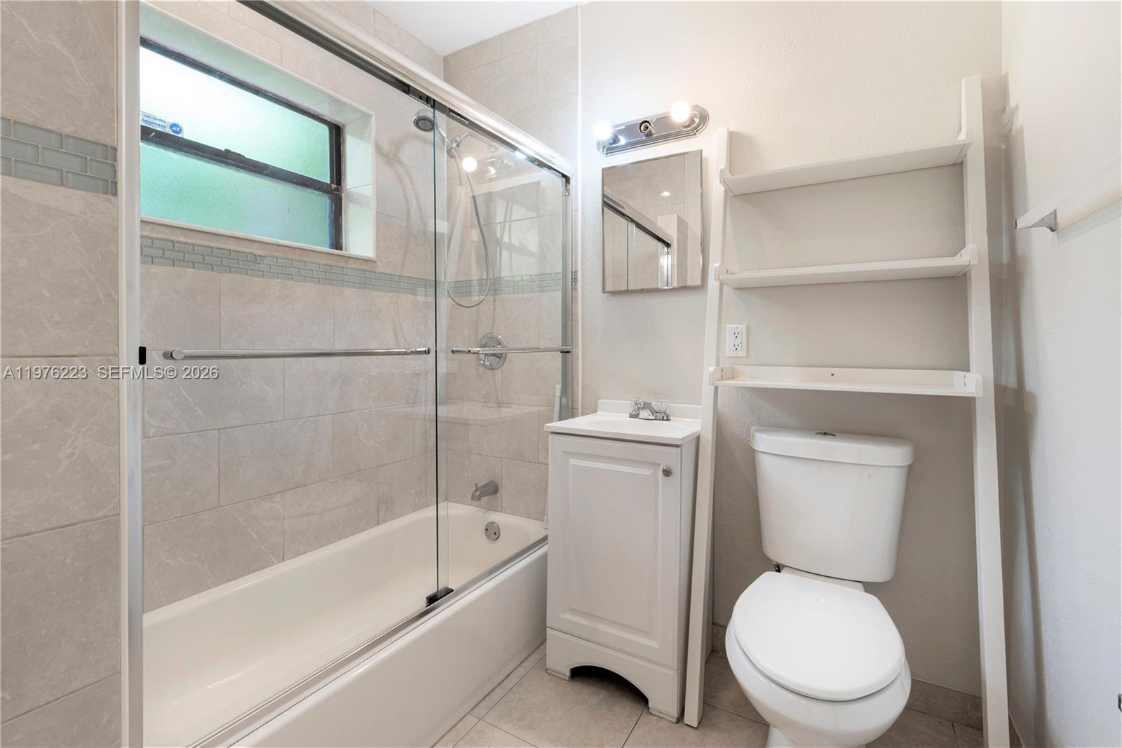 A bathroom features a tiled shower-tub combination, a narrow vanity, and an over-the-toilet shelving unit — 214 Salamanca Ave # 3, Coral Gables FL 33134, CORAL GABLES, FL