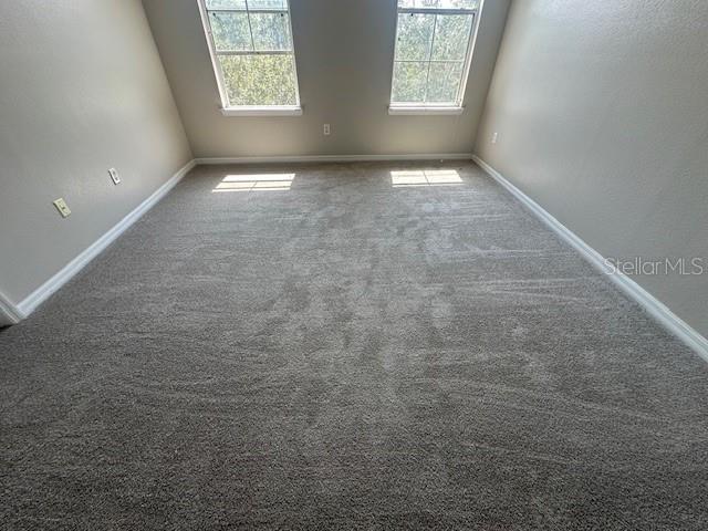An empty room features gray carpeting, light-colored walls, and two windows on the back wall — 11565 MIZZON DRIVE UNIT 308, WINDERMERE, FL