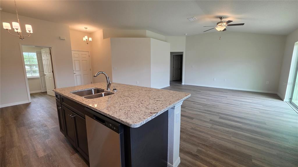 A kitchen island with a granite countertop and stainless steel sink faces an open living area — 668 W WALKERTOWN DRIVE, CITRUS SPRINGS, FL