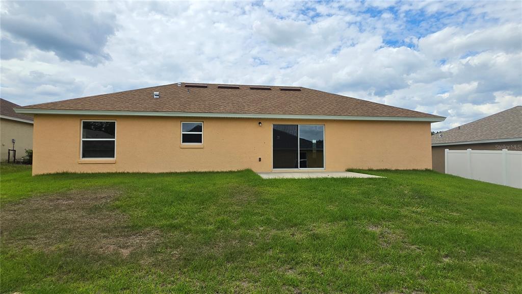 The exterior rear view of a single-story house features a concrete patio and lawn — 668 W WALKERTOWN DRIVE, CITRUS SPRINGS, FL