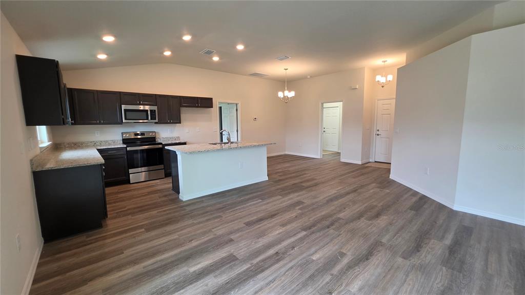 A kitchen with dark cabinets, granite countertops, and an island opens to a living area — 668 W WALKERTOWN DRIVE, CITRUS SPRINGS, FL