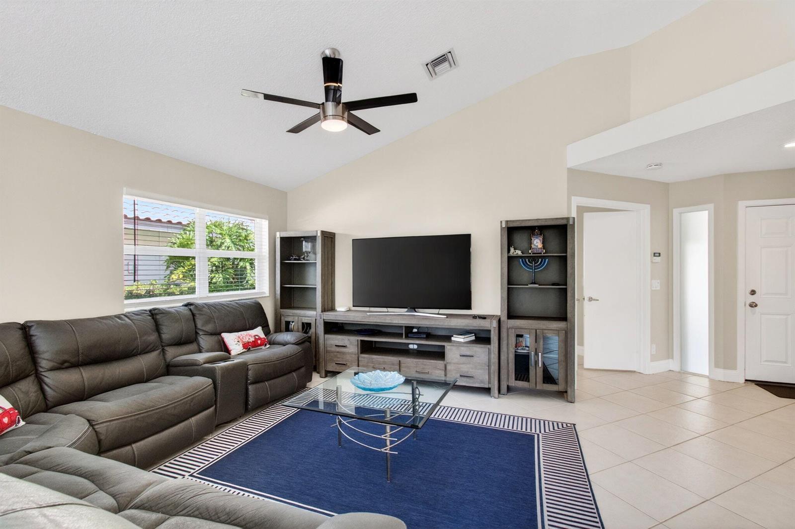 A living room features a gray sectional sofa, a television console, and a blue rug — 2034 NW 52nd Street, Boca Raton FL 33496, BOCA RATON, FL