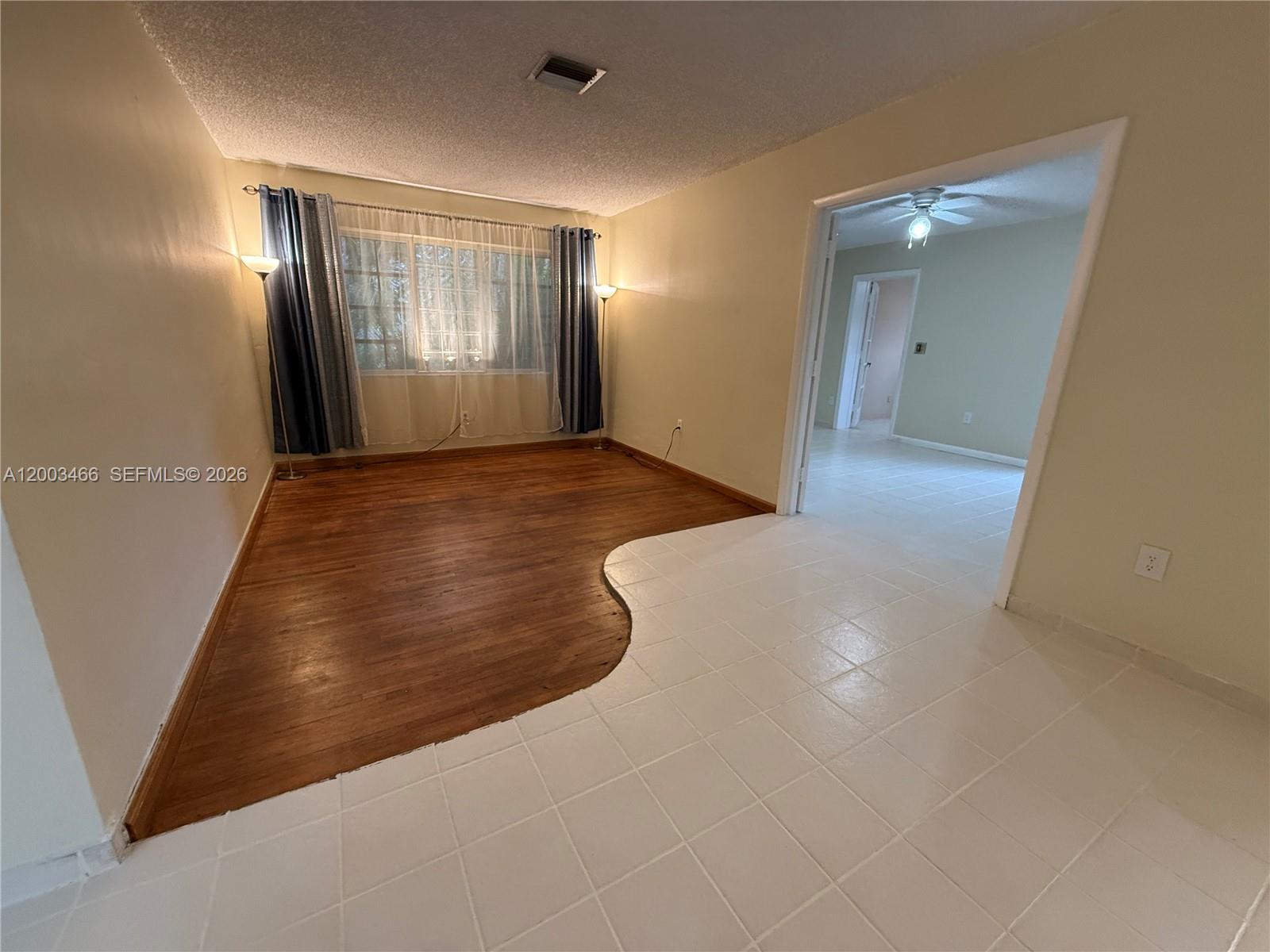 A living room features a curved transition between hardwood flooring and white tile flooring — 1556 San Benito Ave # 1556, Coral Gables FL 33134, CORAL GABLES, FL