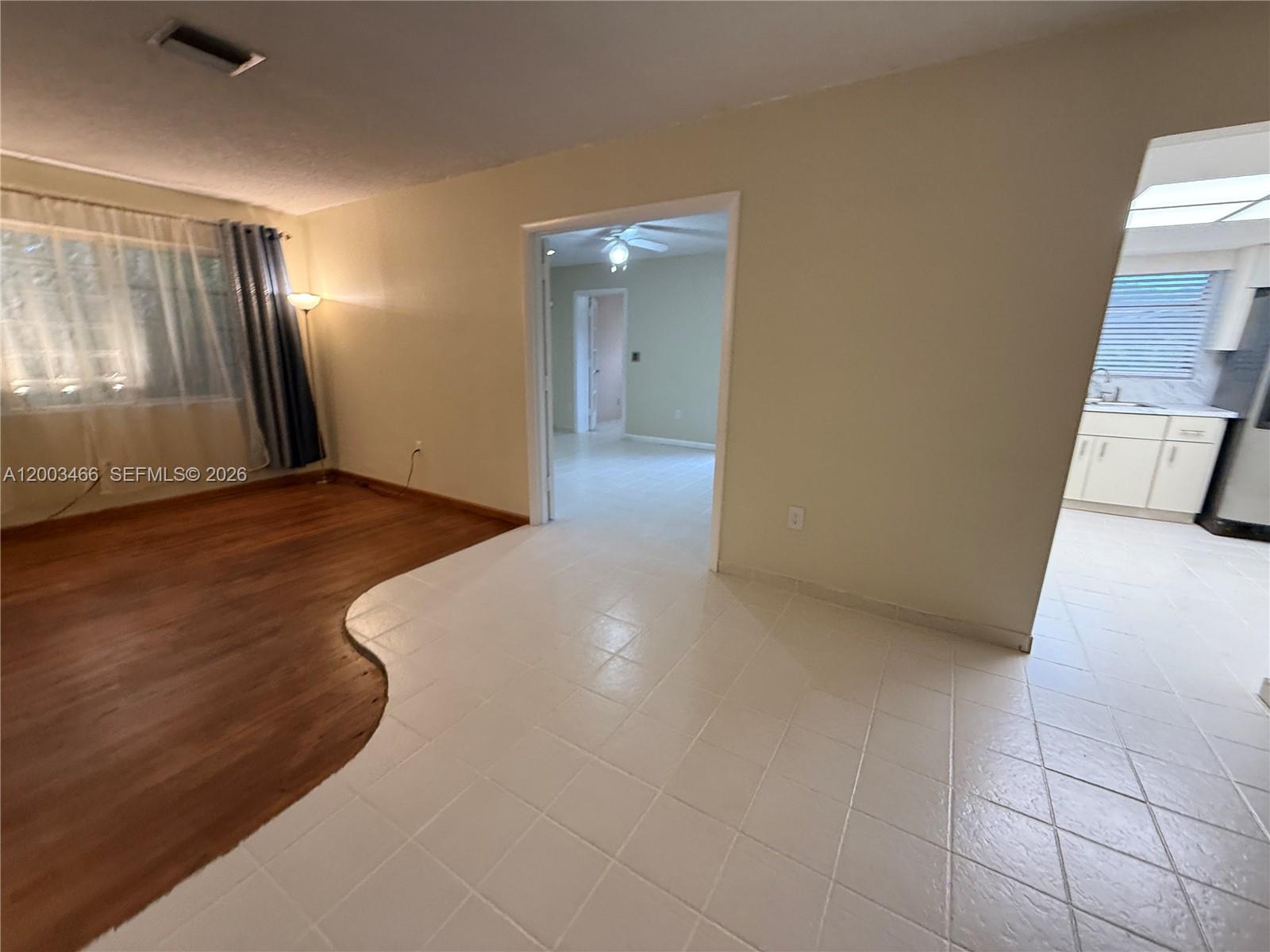 A living room features a curved transition between wood flooring and white ceramic tiles — 1556 San Benito Ave # 1556, Coral Gables FL 33134, CORAL GABLES, FL