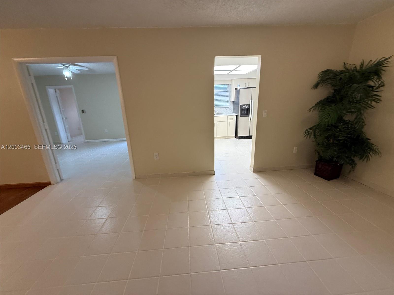 A tiled room features two doorways leading to a kitchen and a hallway with a plant — 1556 San Benito Ave # 1556, Coral Gables FL 33134, CORAL GABLES, FL