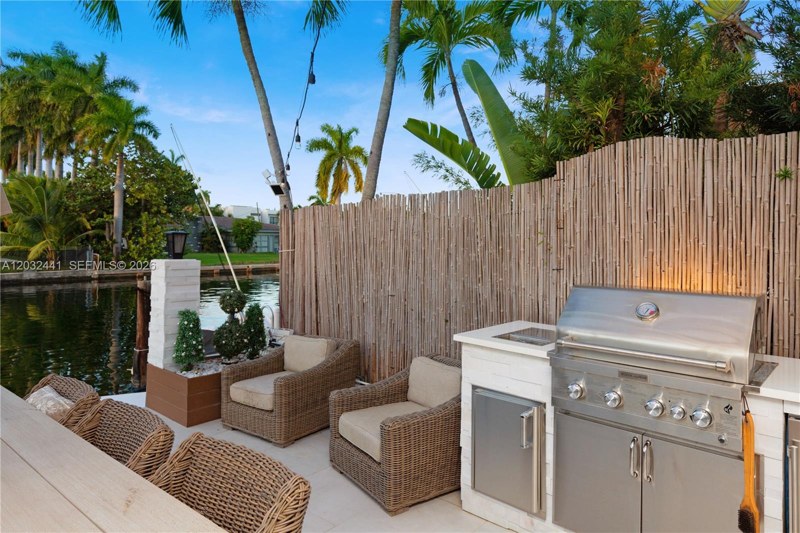 An outdoor patio features a built-in stainless steel grill, wicker seating, and a bamboo fence — 2115 NE 123rd St, North Miami FL 33181, NORTH MIAMI, FL