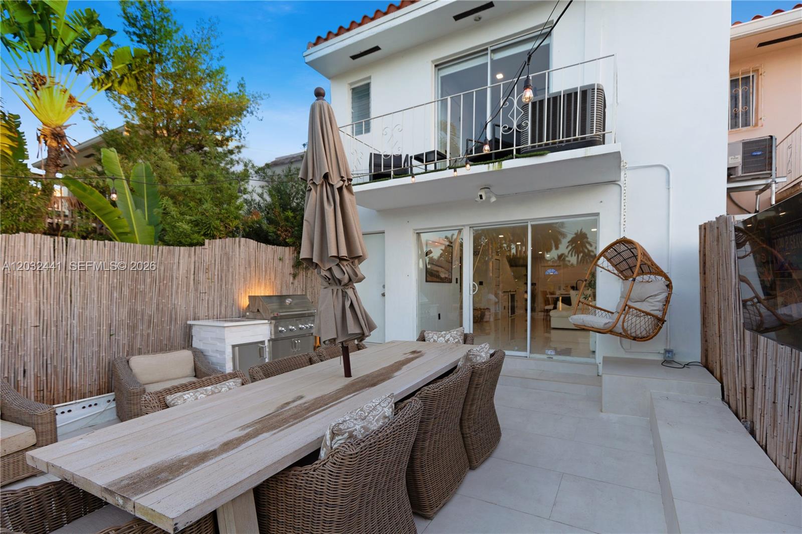 A patio features a wooden dining table, wicker chairs, a hanging chair, and a grill — 2115 NE 123rd St, North Miami FL 33181, NORTH MIAMI, FL
