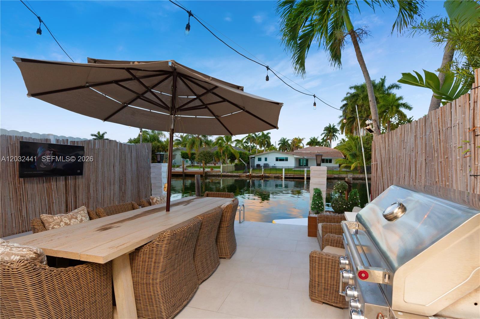 An outdoor patio features a dining table, umbrella, grill, and waterfront view — 2115 NE 123rd St, North Miami FL 33181, NORTH MIAMI, FL