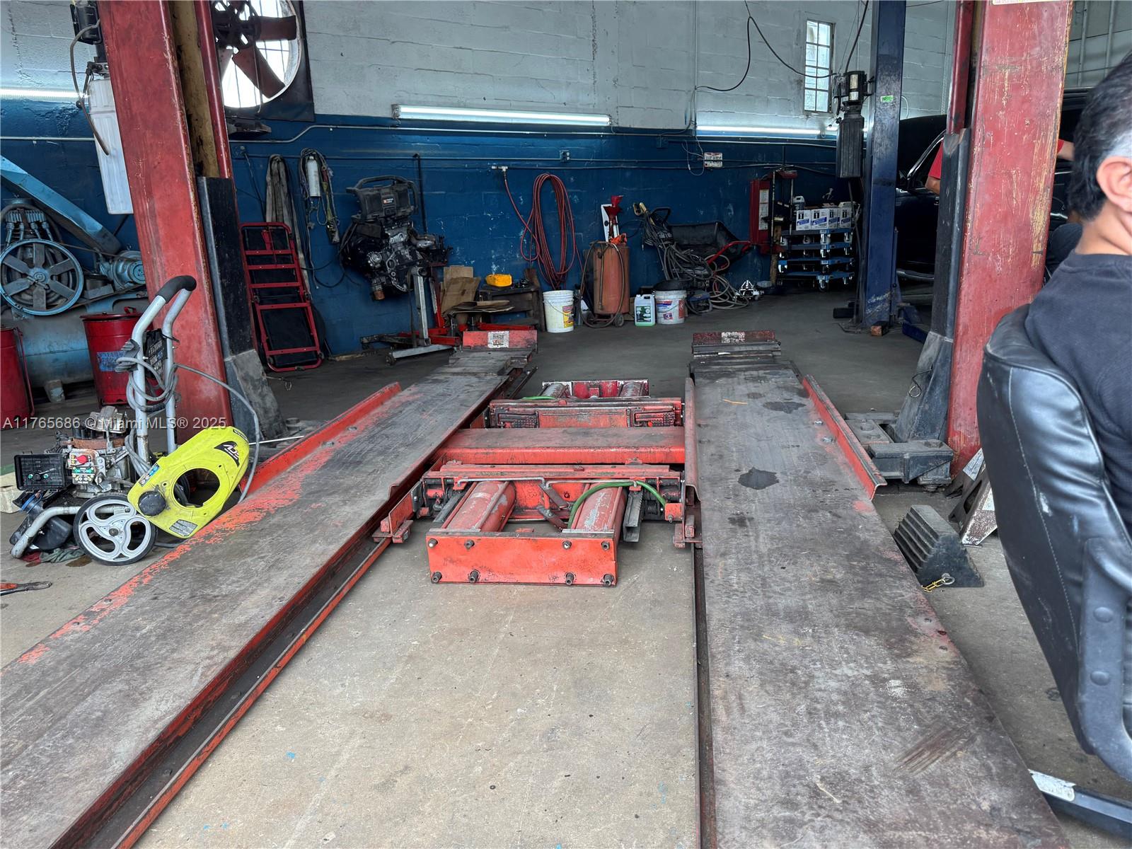 An automotive repair shop features a large red vehicle lift in the center of the room — 2620 SW Ali Baba Ave, Opa-Locka FL 33054, OPA-LOCKA, FL