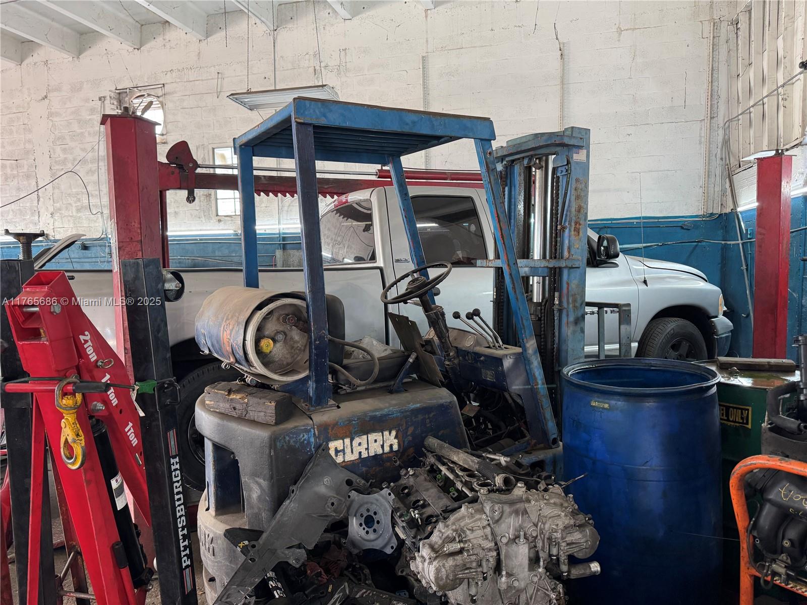 A cluttered garage workspace features a blue Clark forklift, a red engine hoist, and vehicle parts — 2620 SW Ali Baba Ave, Opa-Locka FL 33054, OPA-LOCKA, FL