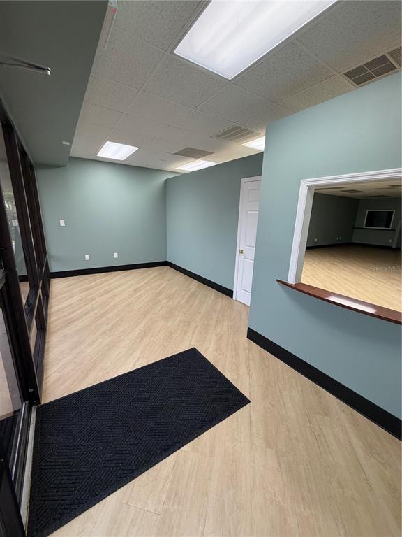 An interior view of an office space with light wood flooring, teal walls, and a window — 4950 HALL UNIT B, ORLANDO, FL