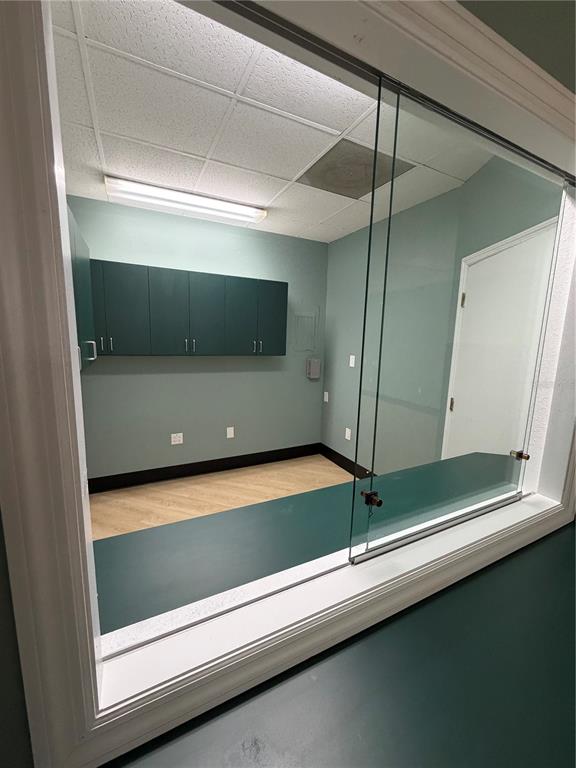 A view through a glass window into a small office with green walls and cabinets — 4950 HALL UNIT B, ORLANDO, FL