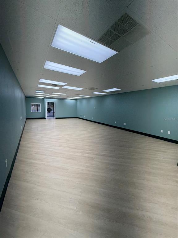An empty commercial space features light wood-look flooring, teal walls, and recessed ceiling lighting — 4950 HALL UNIT B, ORLANDO, FL