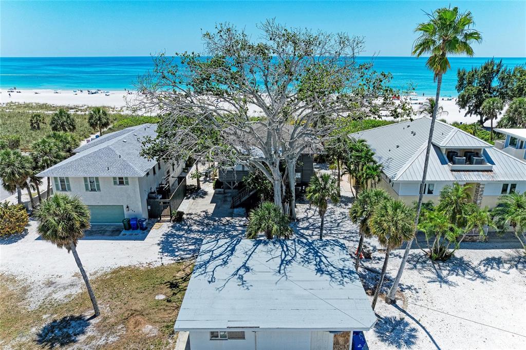 An aerial view shows three houses near a sandy beach with a large central tree — 102 PALMETTO AVENUE, ANNA MARIA, FL