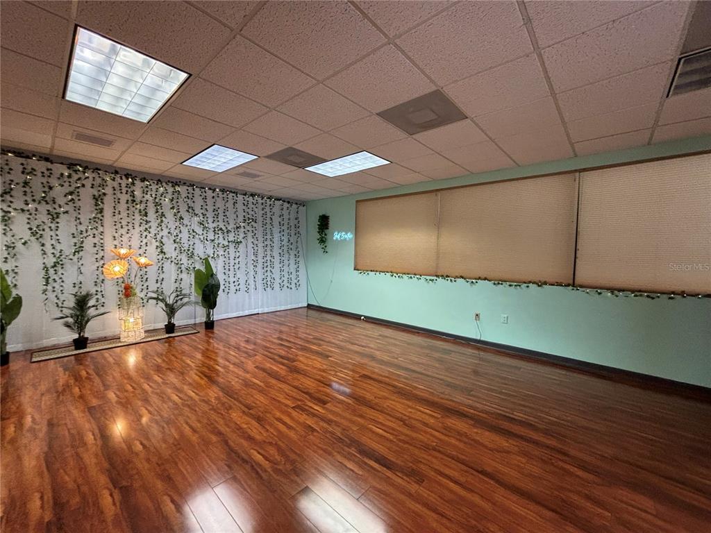 A room with wood-look flooring, a drop ceiling, and walls decorated with hanging greenery — 1750 W BROADWAY STREET UNIT 112, OVIEDO, FL