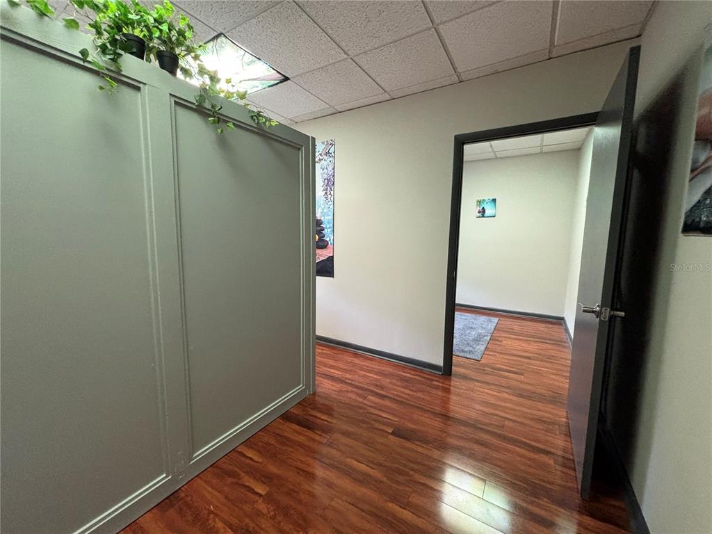 A room with wood-look flooring, a paneled partition wall, and a doorway to another room — 1750 W BROADWAY STREET UNIT 112, OVIEDO, FL